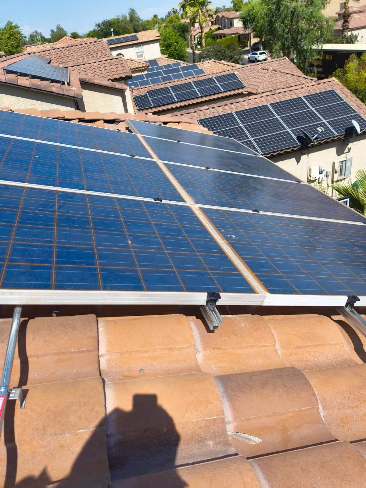 Solar panels reset on a Chandler tile roof, neighboring arrays visible across the street